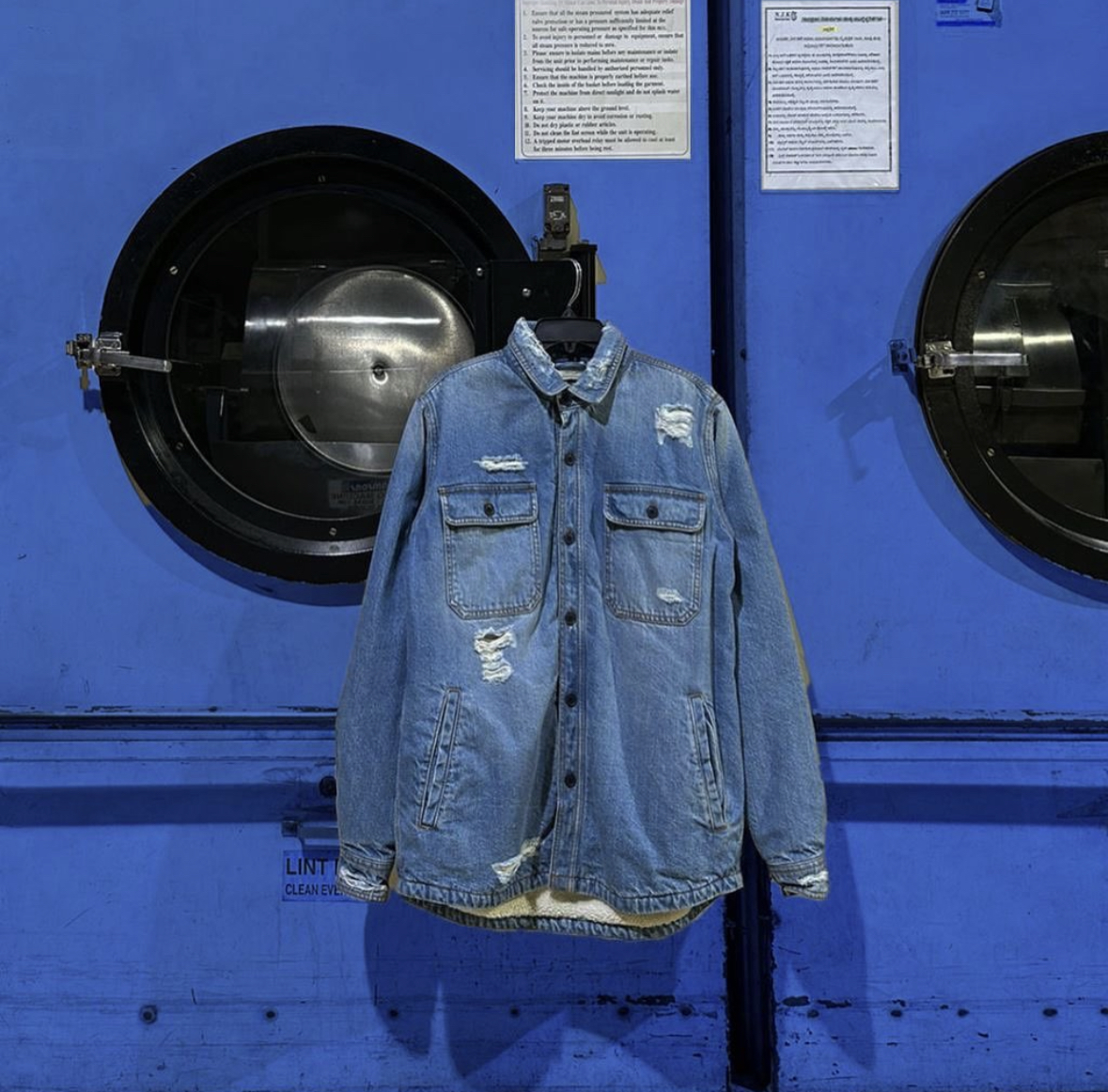 Denim shirt in front of blue laundry machine